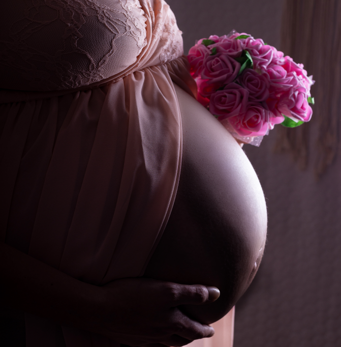 Boudoir Babybauch-Fotoshooting. Werdende Mama hält liebevoll und stolz ihren Bauch.