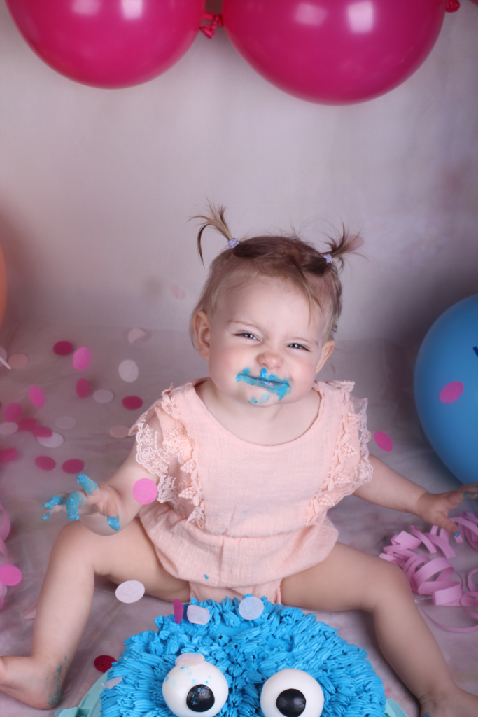 Die kleine Mara hat Freude beim Kuchen-Matschen bei ihrem Cake-Smash-Fotoshooting.